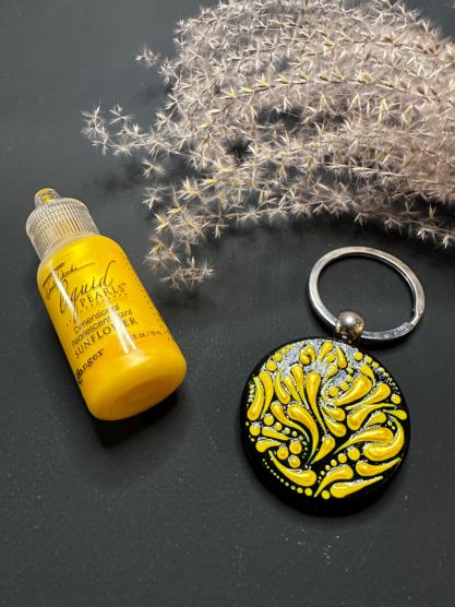 Gelber Nagellack und ein Schlüsselanhänger mit schwarzem Grund und gelben Mustern.