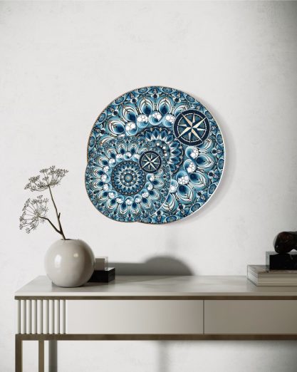 Bunte Wanddekoration mit spiralförmigem Muster, daneben eine Vase auf einem Tisch.