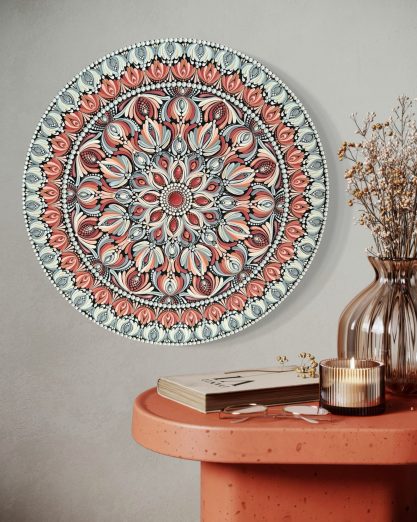 Bunte, runde Wanddekoration mit floralen Mustern an einer Wand über einem dekorativen Tisch.